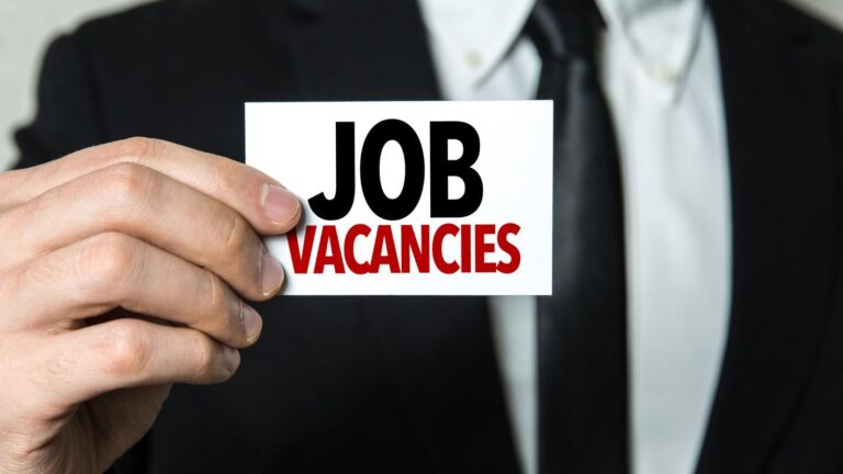 Professional businessman in suit holding job vacancies card representing genuine vacancy requirement UK 2025 compliance for employers
