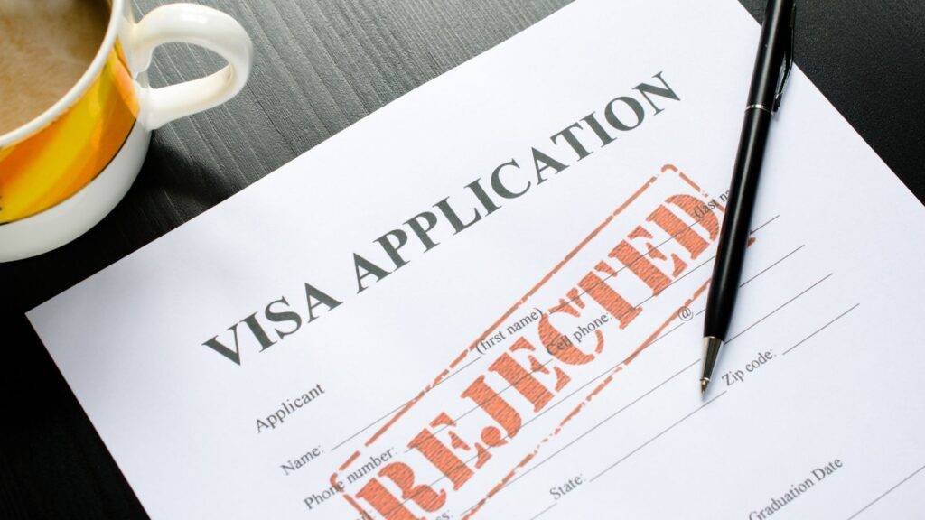 UK visa refusal reasons 2025 – rejected visa application form with stamp and pen