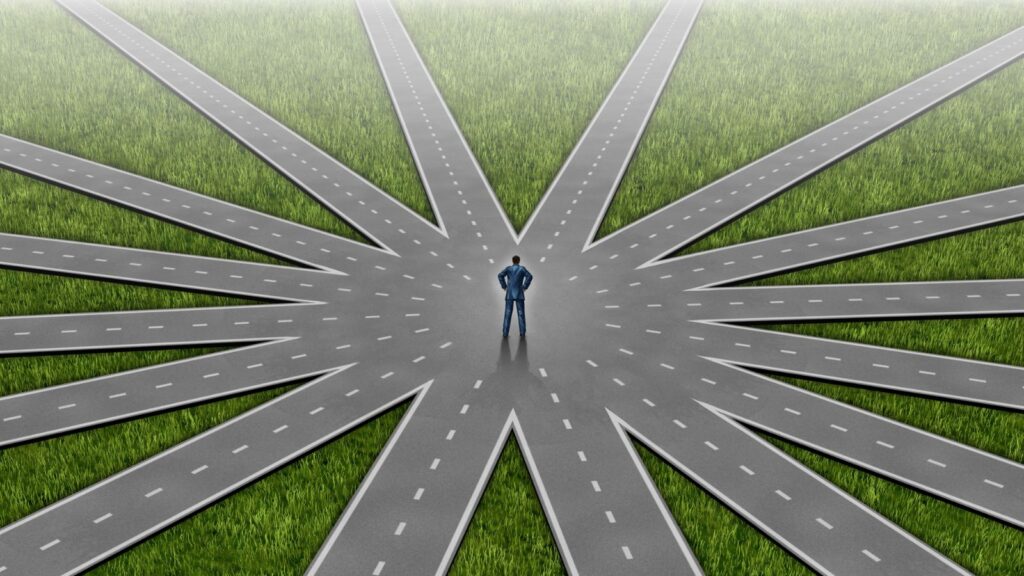 Aerial view of person at center of multiple radiating roads representing switching visa categories to skilled worker visa uk 2025 pathway decisions and route choices