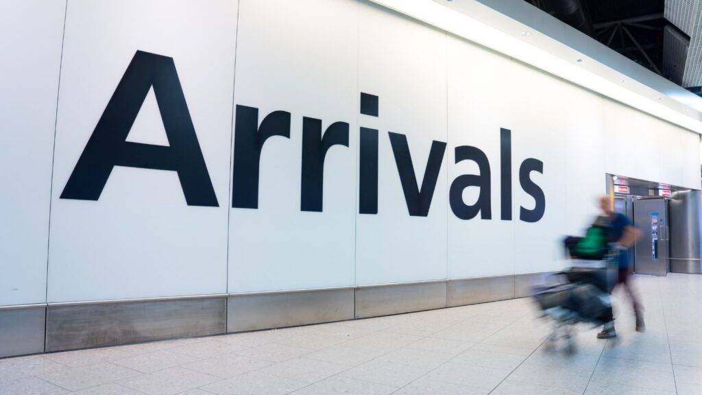 Airport arrivals sign with traveler representing Afghan resettlement UK 2025 ARAP and ACRS schemes successful relocation