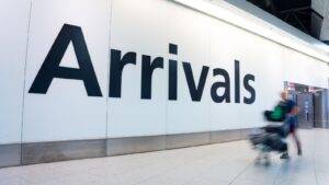 Airport arrivals sign with traveler representing Afghan resettlement UK 2025 ARAP and ACRS schemes successful relocation