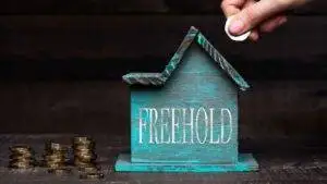 Turquoise House Model With Freehold Text And Coin Stacks Representing Buy Freehold Leasehold House Uk 2025 Purchase Costs And Enfranchisement Process