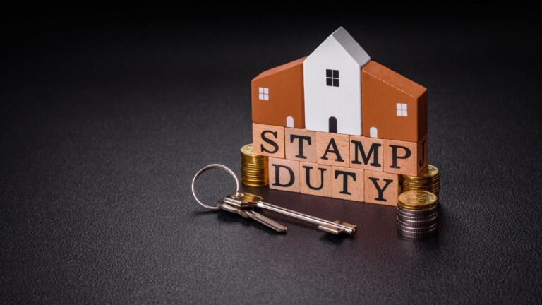 House model with stamp duty wooden blocks, gold coins and property keys representing SDLT additional property surcharge 2025 calculations and policy changes
