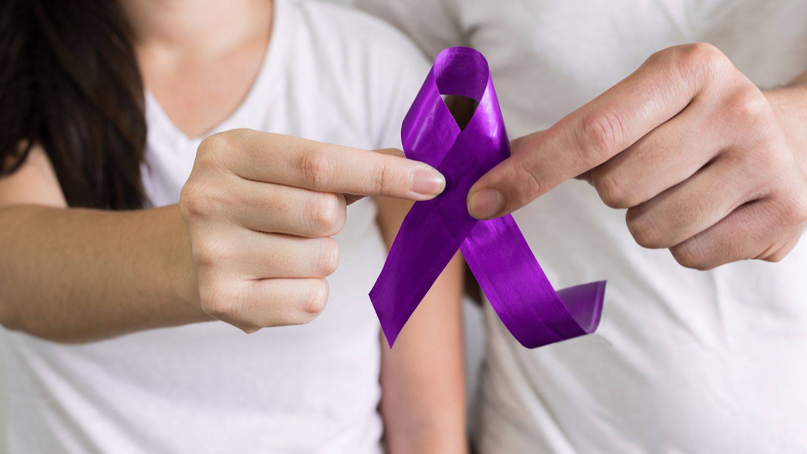 Hands holding purple awareness ribbon symbolizing violence against women and girls UK 2025 government strategy and legal framework