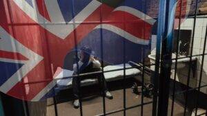 Person in detention cell behind bars with UK flag representing immigration detention discrimination UK 2025 Equality Act protections