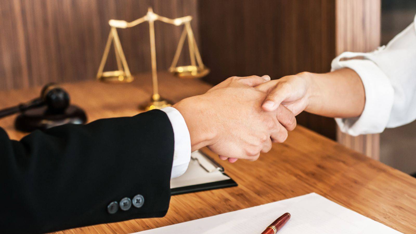 Professional handshake with scales of justice representing supportive legal consultation for employment rights illegal workers UK 2025