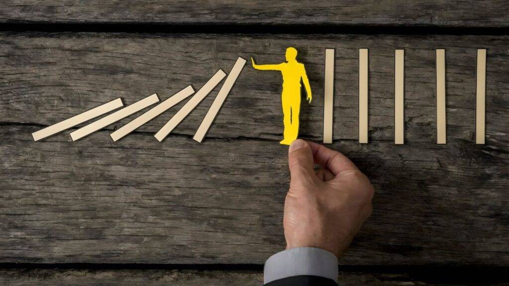 Yellow figure stopping falling dominoes representing criminal disclosure solicitors UK preventing due process failures and protecting defendant rights under CPIA 1996