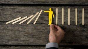 Yellow figure stopping falling dominoes representing criminal disclosure solicitors UK preventing due process failures and protecting defendant rights under CPIA 1996