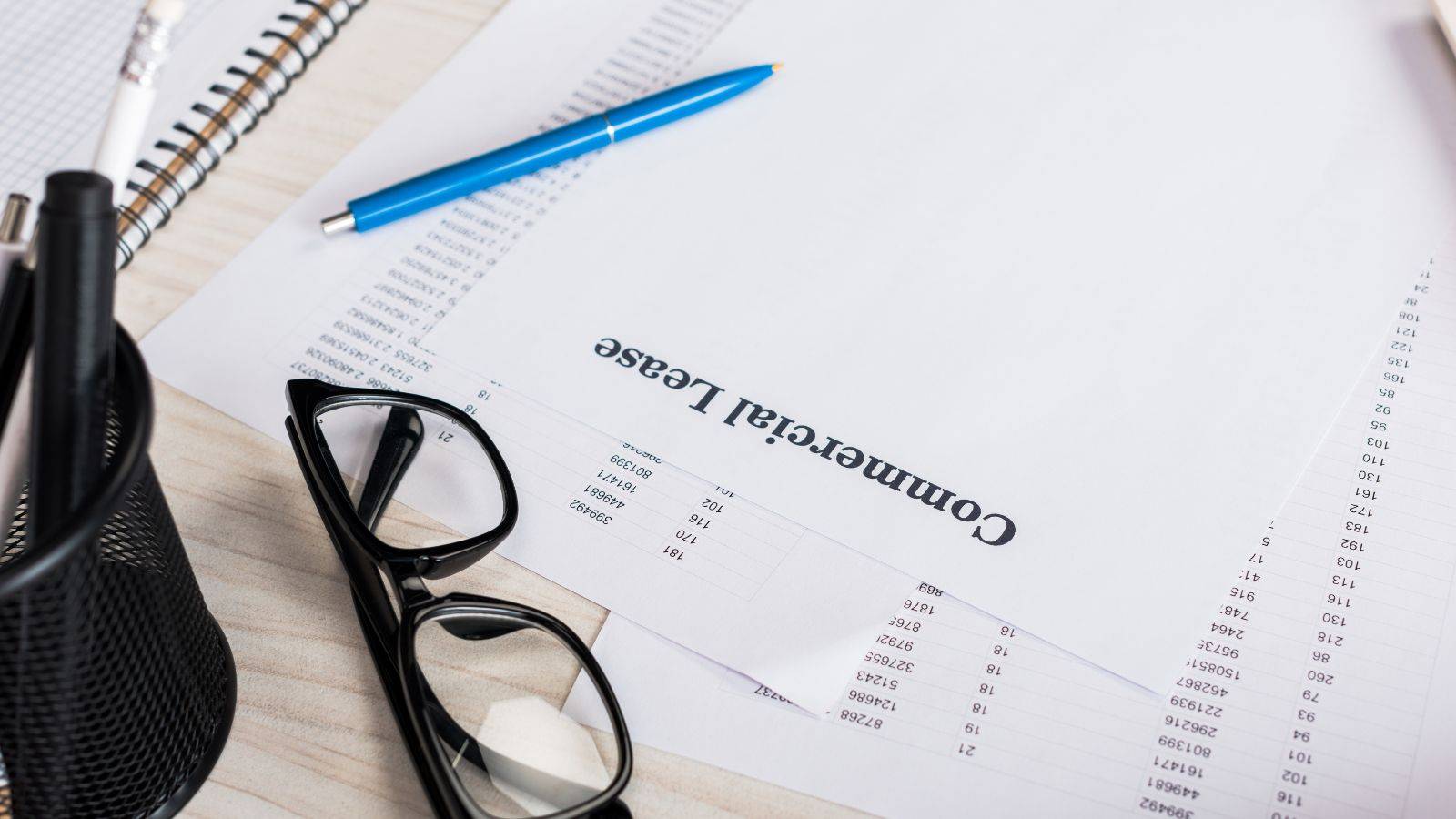 Commercial lease document with reading glasses and blue pen representing commercial lease agreement guide UK for business tenants reviewing property rental terms