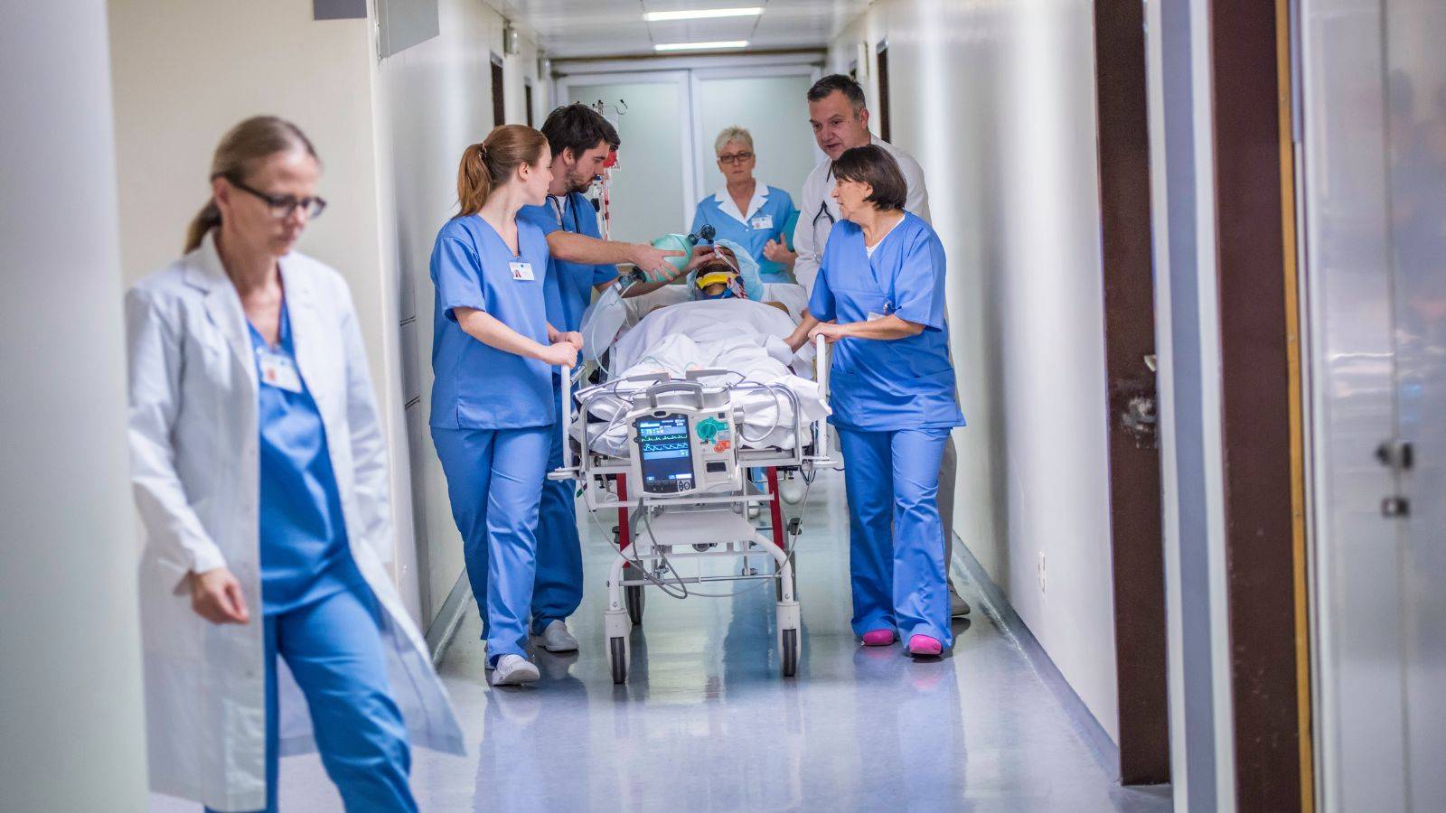 Medical team transporting patient through hospital corridor representing Health and Care Worker visa UK 2025 eligible healthcare professionals in NHS emergency care setting