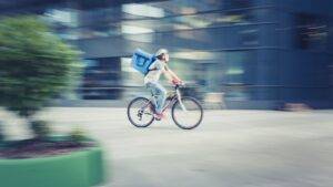 Delivery cyclist in motion with blue backpack representing gig economy worker rights UK 2025 employment status protections