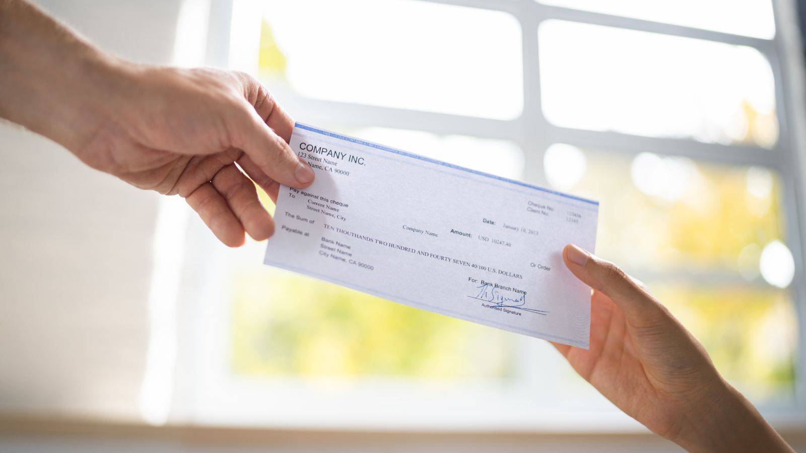 Hands exchanging compensation cheque representing amigo loans scheme 2025 final payments and unclaimed compensation recovery