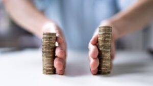 Person comparing two different-sized stacks of coins representing financial disclosure divorce UK 2025 Form E asset comparison and unequal financial positions