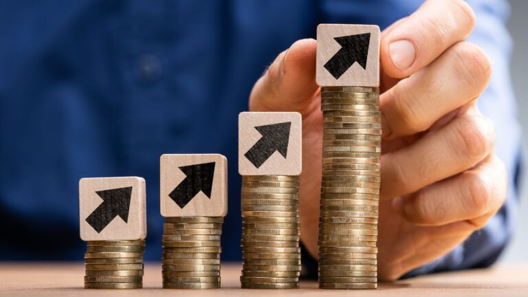 Stacked coins with upward arrows representing skilled worker minimum salary requirements progression and threshold achievement