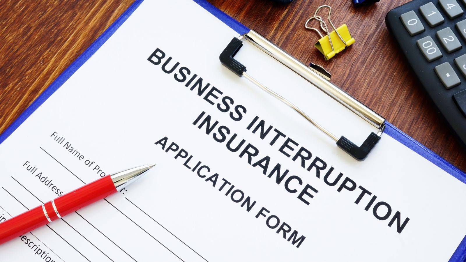 Business interruption insurance application form with calculator and pen representing can i claim business interruption insurance 2025