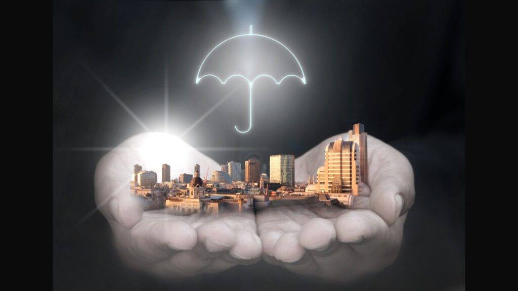Protective hands with umbrella covering city skyline representing what does business interruption insurance cover mean 2025 protection guide