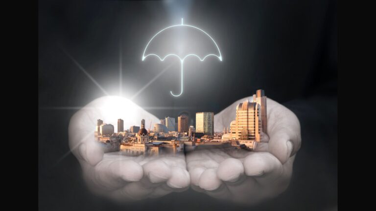 Protective hands with umbrella covering city skyline representing what does business interruption insurance cover mean 2025 protection guide