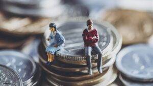 Miniature couple figurines separated by pile of coins representing financial mediation divorce UK 2025 disputes over asset division and financial settlement