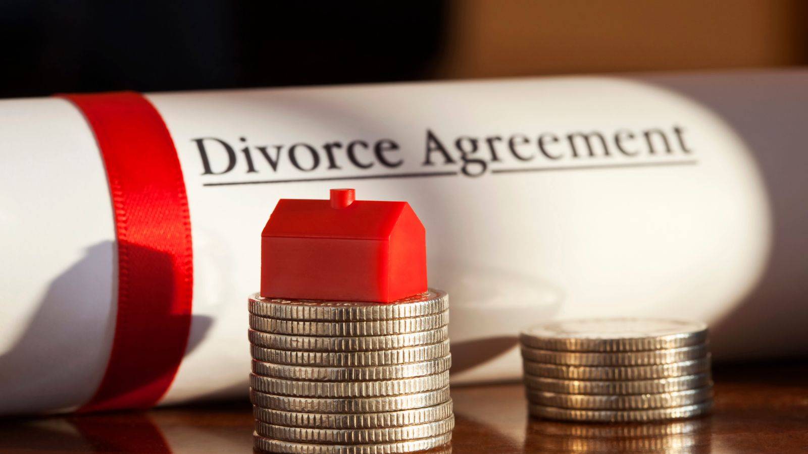 Divorce agreement document with red house model on coin stacks representing international divorce UK 2025 property and financial settlement