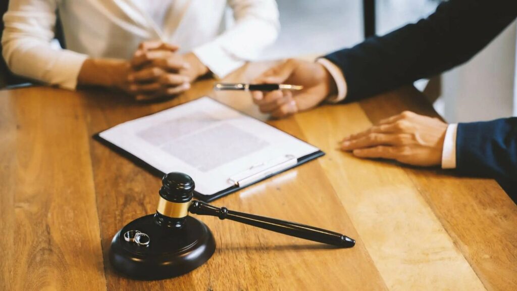 Wedding rings and judge's gavel on consultation table representing financial orders divorce UK 2025 consent order proceedings with couple and solicitor