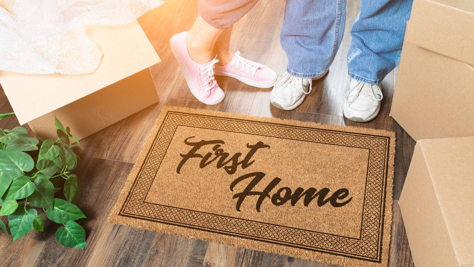 First home doormat with moving boxes representing buying first home UK process for first-time buyers