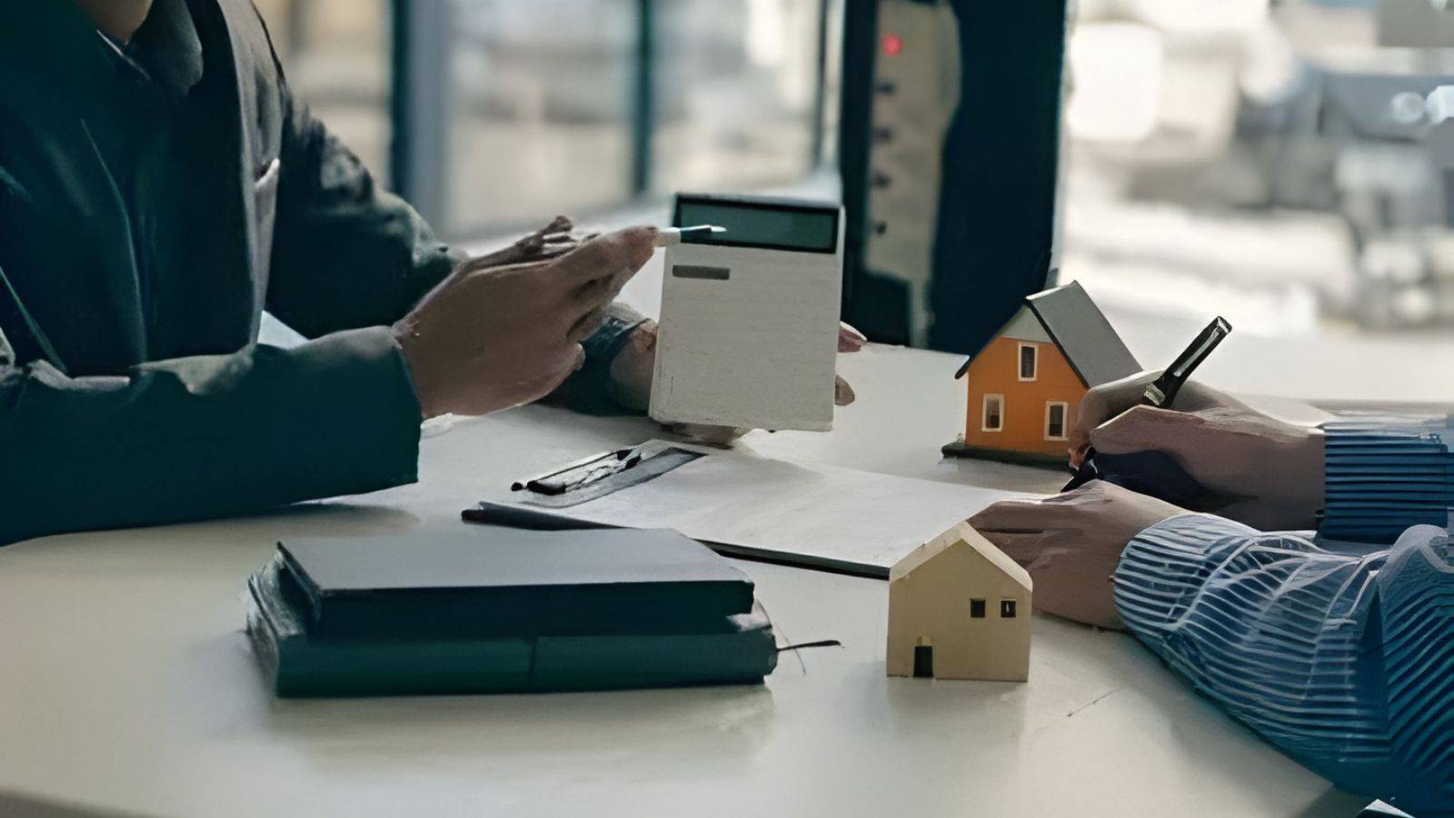 Property professionals discussing home mover conveyancing UK 2025 with model houses calculator and legal documents