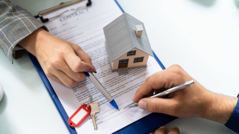 Professional signing property documents with house model and keys representing comprehensive purchasing leasehold property 2025 guide legal process