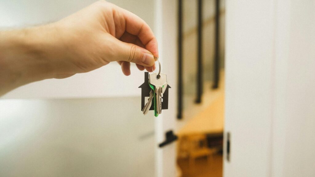 Hand holding property keys with house keychain representing surrender of lease UK 2025 process and tenant return of possession to landlord
