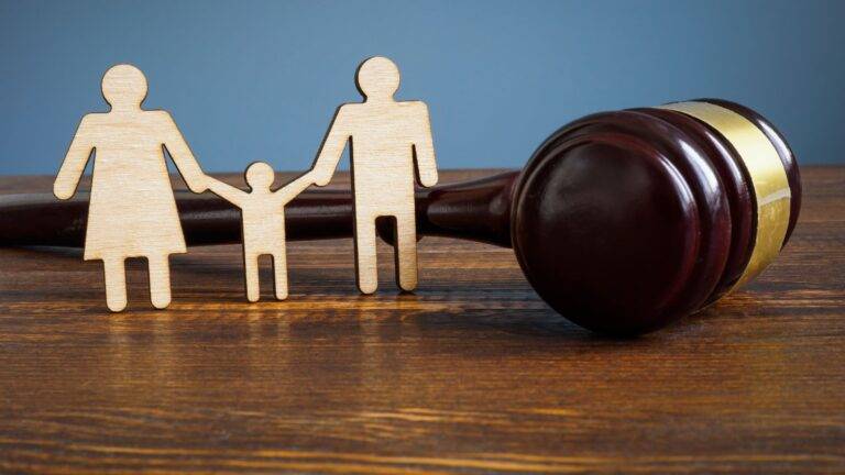 Wooden family figures with judge's gavel representing child adoption requirements UK 2025 legal procedures and court processes
