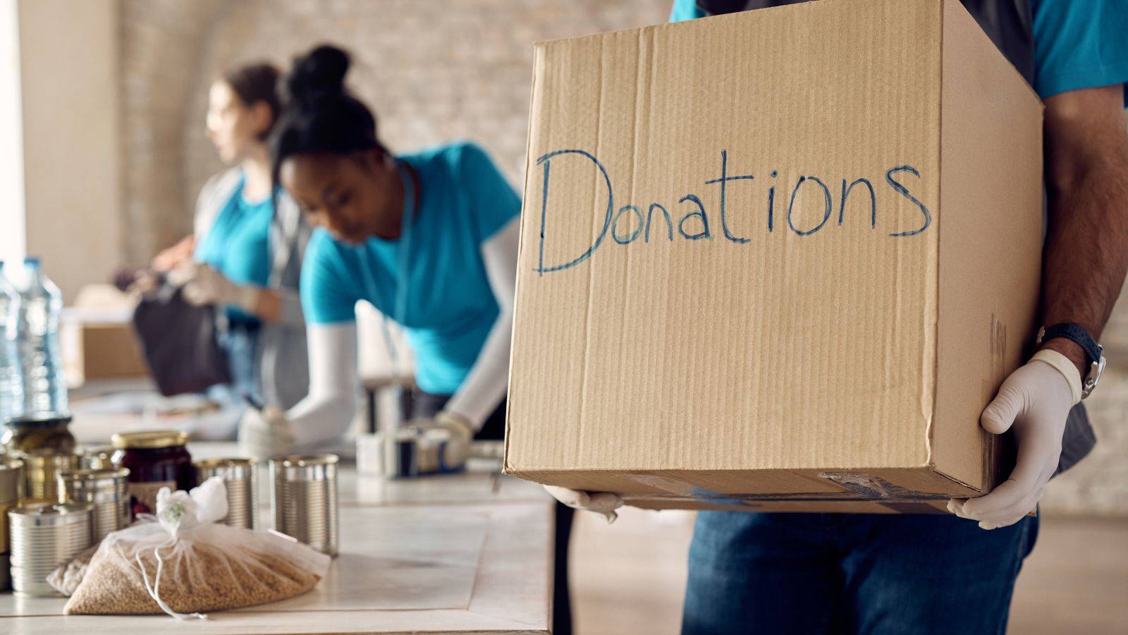 Charity worker holding donations box in UK warehouse representing Charity Worker Visa UK voluntary work opportunities