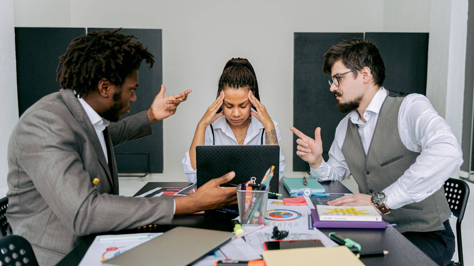 Stressed director holding head during heated boardroom dispute with confrontational gestures representing UK director disputes 2025 conflict resolution and company law procedures