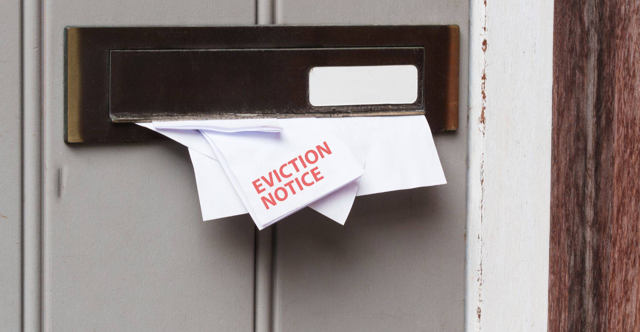 Eviction notice being delivered through mail slot representing property evictions solicitors UK 2025 legal services for landlords