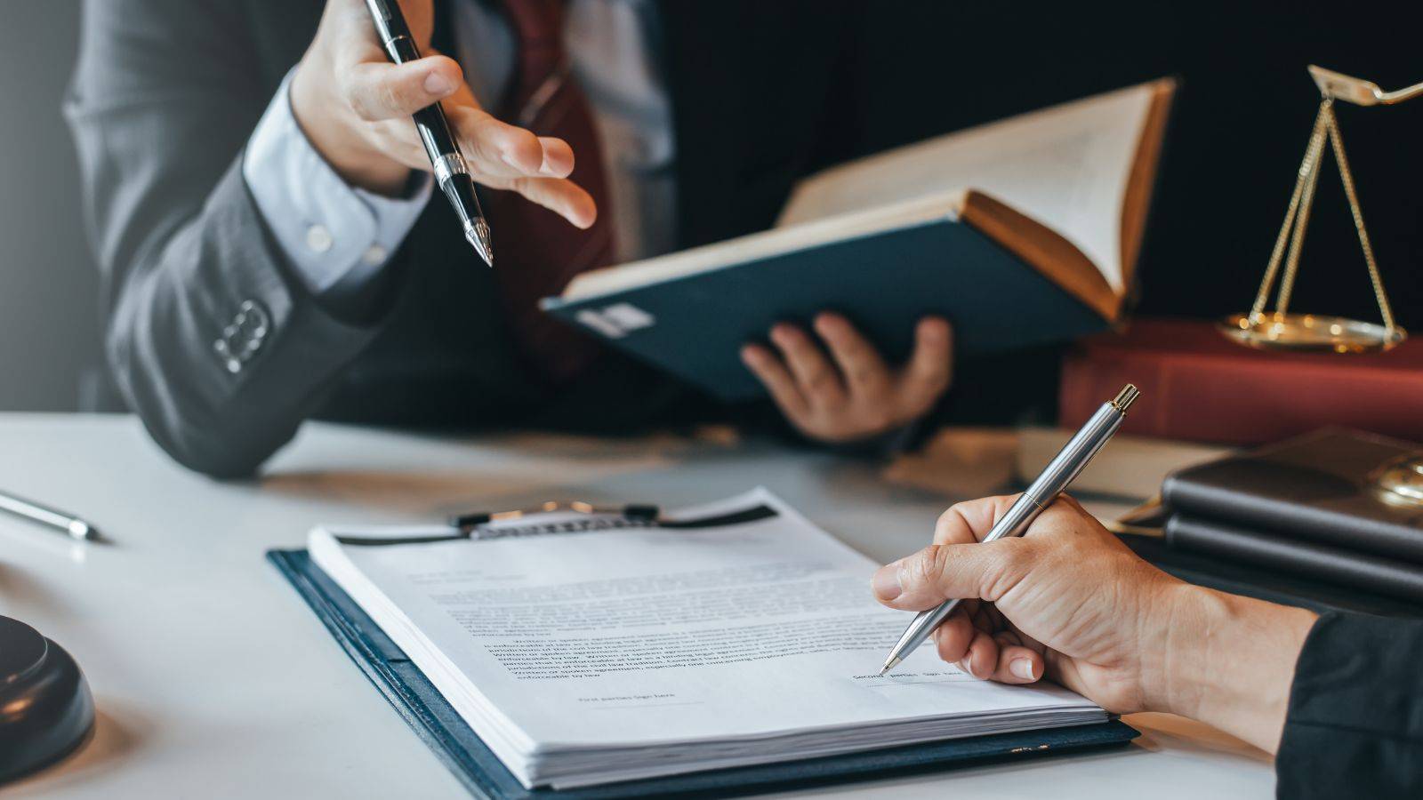 Legal professional reading law book and writing on commercial litigation documents with scales of justice representing commercial litigation solicitors UK 2025 services