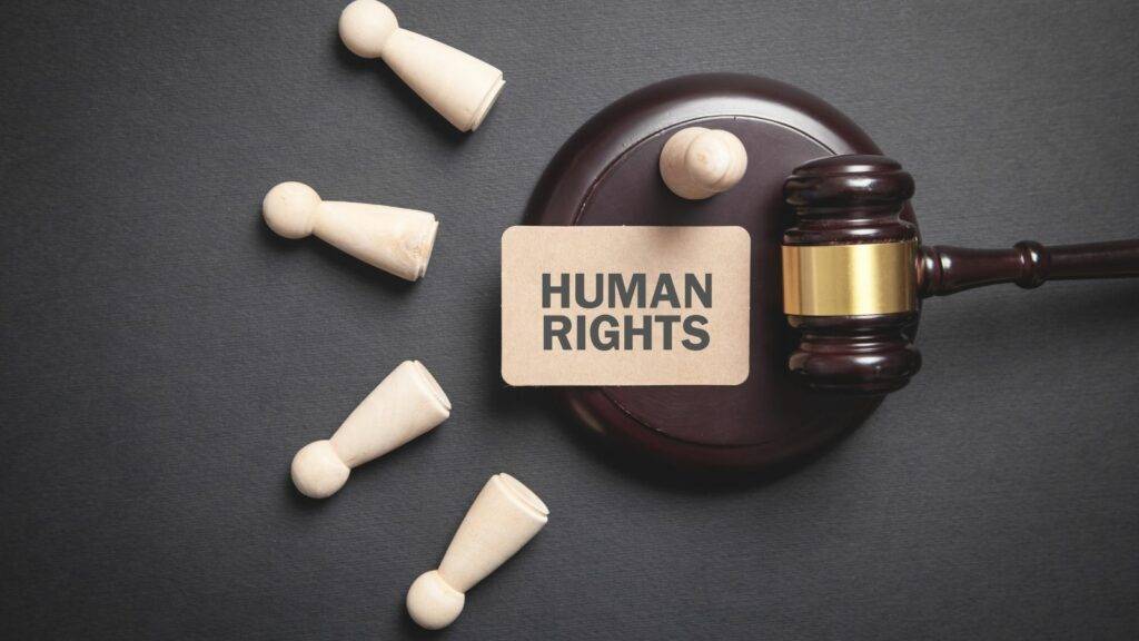 Human rights concept with judge's gavel and scattered wooden figures symbolizing justice and protection of vulnerable individuals.