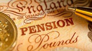 Uk Pension Sharing Concept With Pound Coin And Note Under Pen
