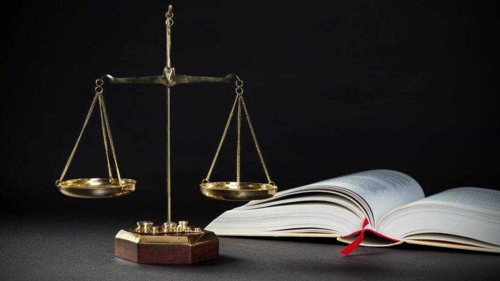 Brass balance scales and an open legal book symbolising administrative review of UK visa decisions