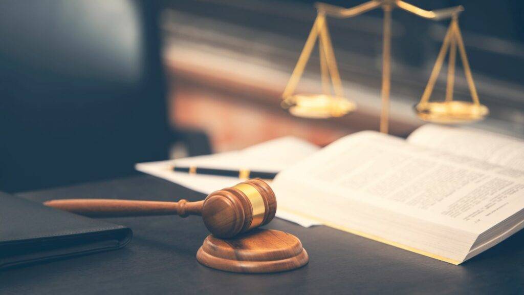 Wooden gavel, open law book, and balance scales symbolising judicial review of UK visa refusals