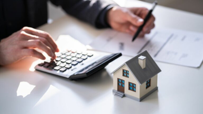 Landlord calculating tax relief on domestic items using a calculator next to a model house