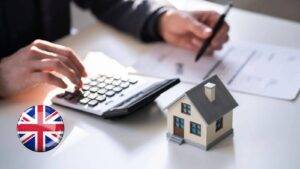 Person calculating landlord tax relief with calculator house model documents and UK flag representing replacement of domestic items relief UK 2025