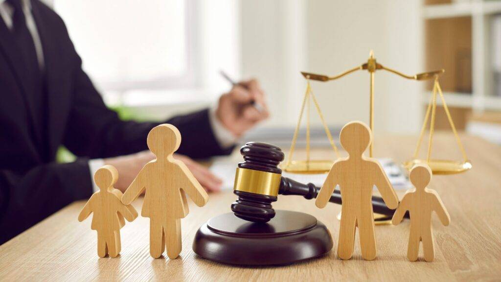 Professional legal office showing wooden family figures with gavel and scales of justice representing child contact agreement solicitors UK 2025 services