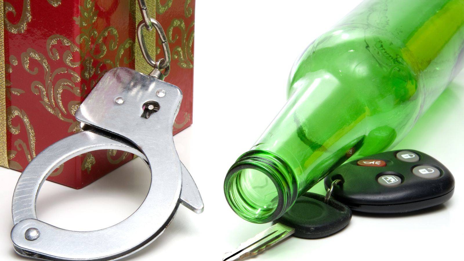 Handcuffs and alcohol bottle with car keys representing UK driving offences penalties 2025 criminal consequences
