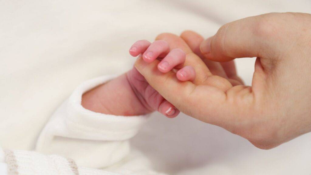 Protective hands holding newborn baby representing birth injury compensation calculator UK 2025 legal support