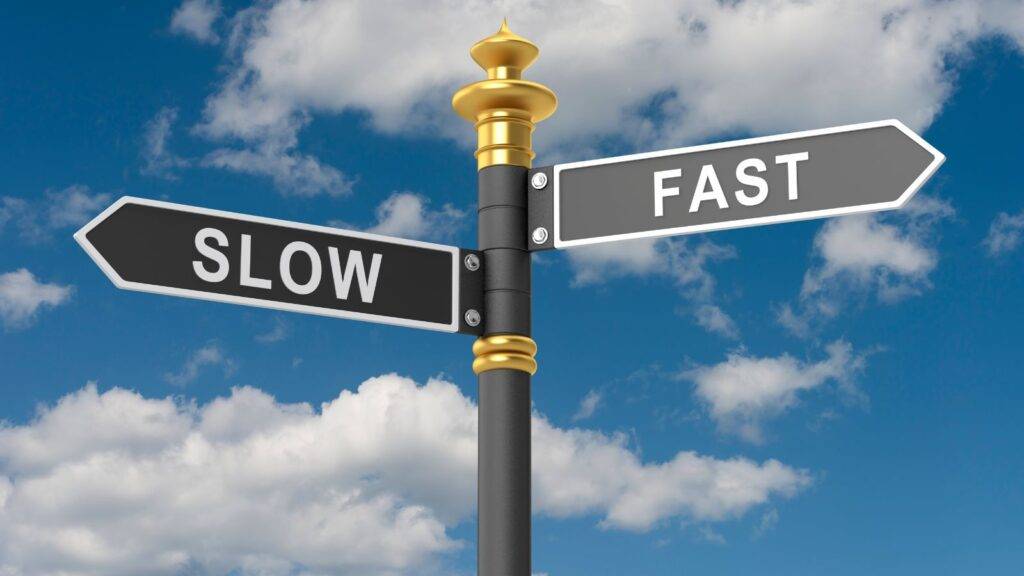Road directional signs showing SLOW and FAST options representing UK visa premium processing 2025 choice between standard and Priority services