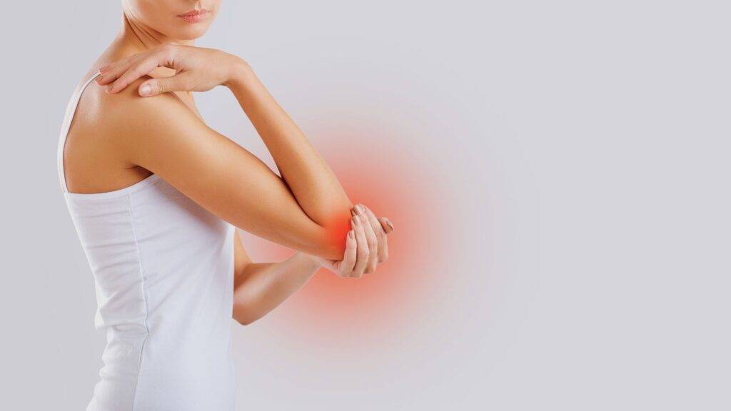 Professional woman showing elbow pain area representing elbow injury compensation calculator UK claims and tennis elbow workplace injury assessment