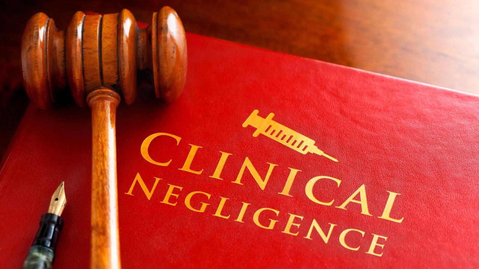 Clinical negligence legal book with gavel and fountain pen showing medical negligence compensation claims UK 2025 professional solicitor expertise and legal authority