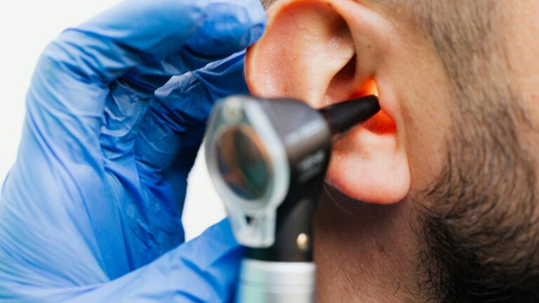 Healthcare professional ENT specialist conducting comprehensive hearing examination with otoscope on patient for industrial deafness and hearing loss compensation UK 2025 legal claim diagnostic assessment and medical evidence documentation