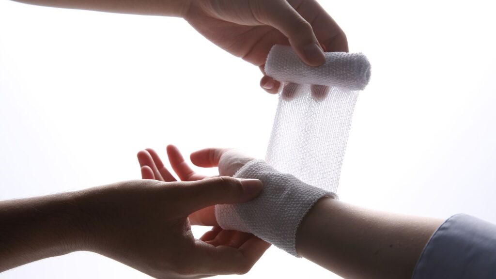 Healthcare professional applying specialized bandaging treatment to patient's injured wrist during clinical assessment for wrist injury compensation UK 2025 legal claim documentation and medical evidence