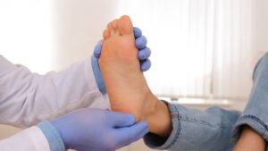Healthcare professional examining patient's foot sole using clinical palpation technique with medical gloves for foot injury compensation UK 2025 diagnostic assessment