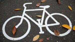 Painted bicycle lane symbol on UK road surface with autumn leaves representing bicycle accident compensation UK legal rights and cycling infrastructure protections