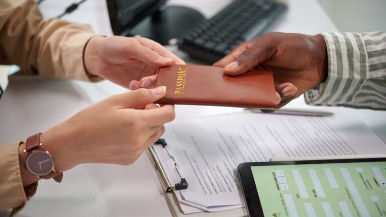 Home 3 Passport Being Handed To Immigration Official At Document Verification Desk Representing Certificate Of Entitlement Uk 2026 Application Process